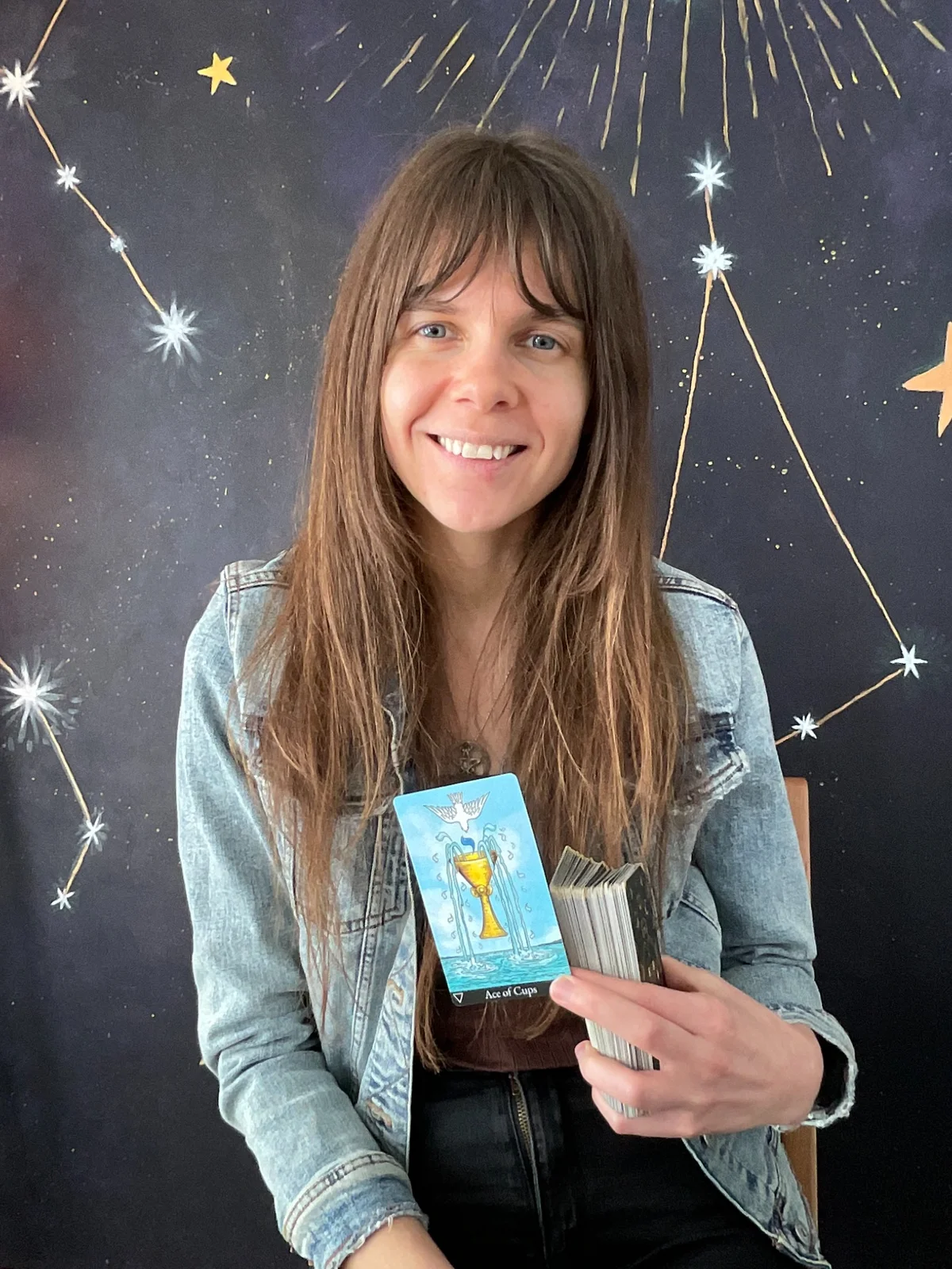 Rozzebud smiling while holding a tarot card