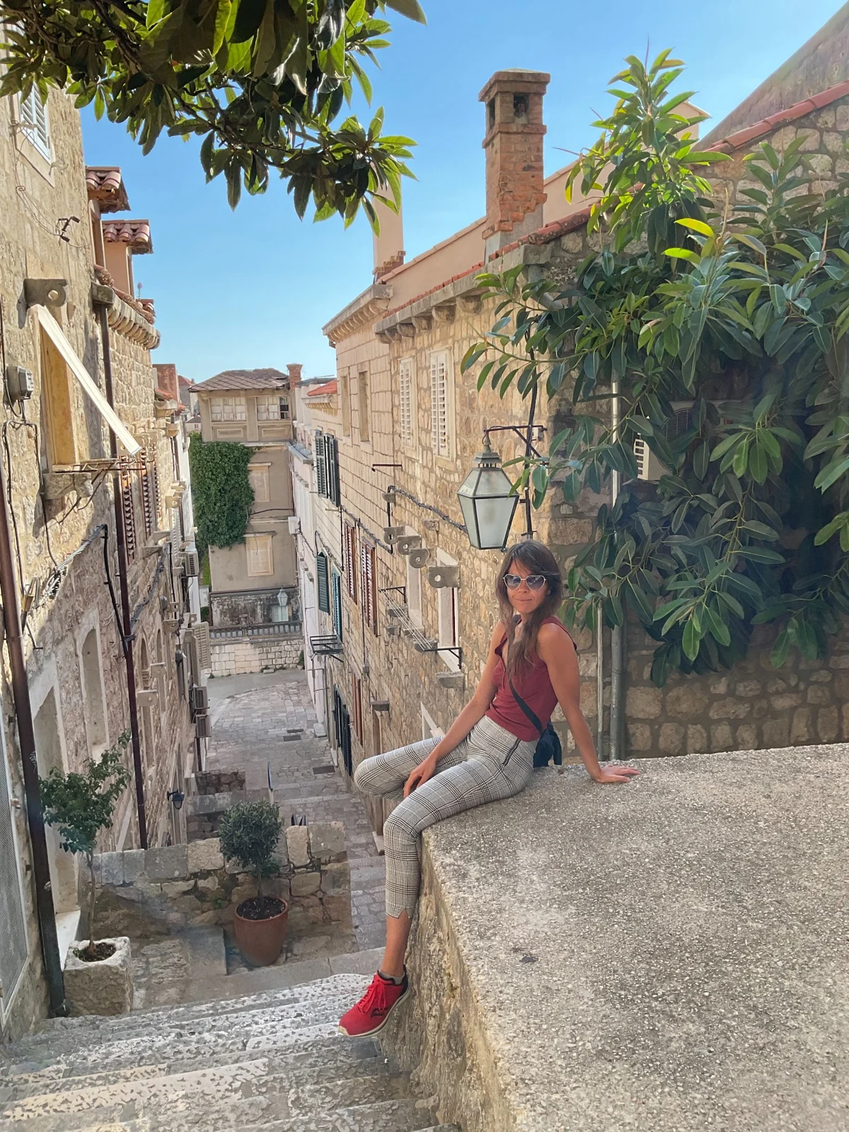 Rozzebud seated beside a stone staircase in a sunlit town